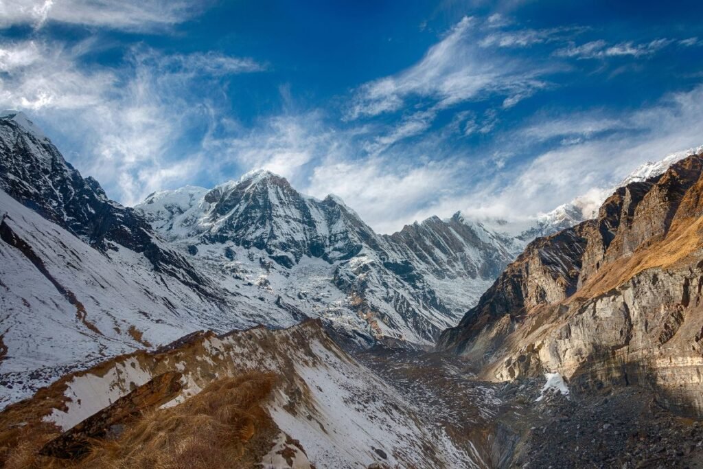 "Snow-covered peaks of Annapurna Sanctuary under a vibrant blue sky, viewed from a high-altitude trail near Ghandruk, Nepal"