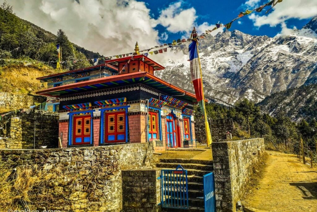 "A vibrant, traditional Himalayan monastery with colorful doors and prayer flags, set against a dramatic backdrop of snow-covered mountains in Chaurikharka, Nepal"